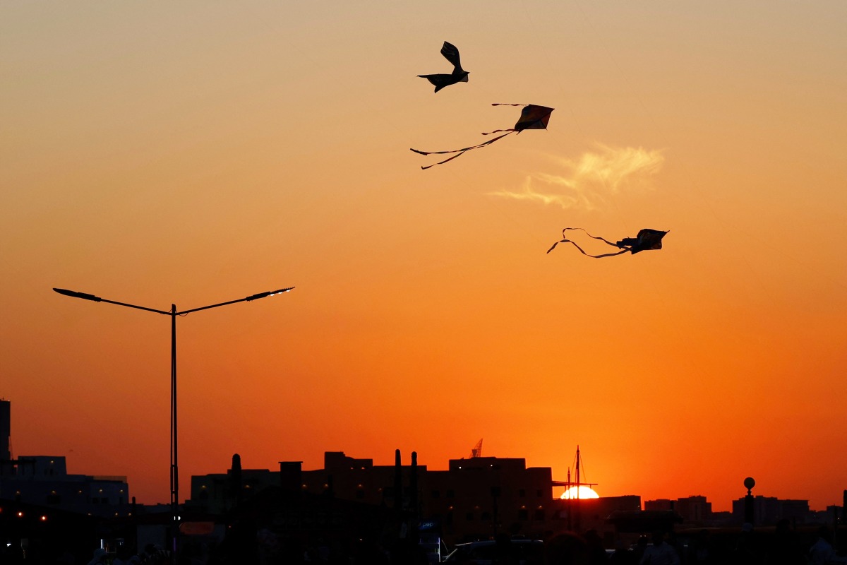 Kites are silhouetted against the setting sun during the 'Qatar Kite Festival 2025' at Old Doha Port in Doha on January 21, 2025. (Photo by Karim JAAFAR / AFP)