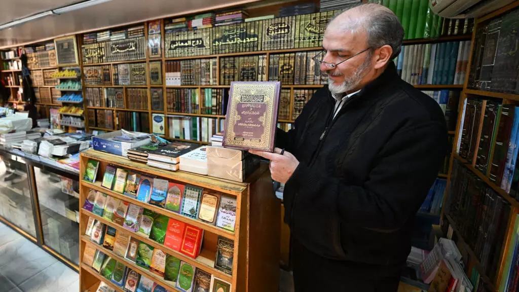 A bookseller shows a volume that was reportedly banned during the rule of Syria's ousted president Bashar Al Assad. (Pic: Louai Beshara / AFP) 