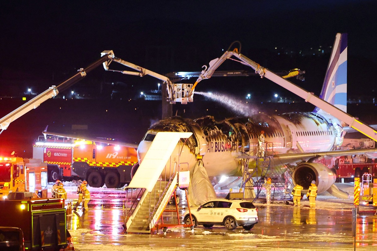 Firefighters work to extinguish a fire that broke out on an Air Busan passenger plane bound for Hong Kong, at Gimhae International Airport in Busan on January 28, 2025. Photo by YONHAP / AFP