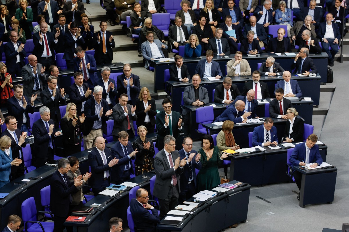 Leader of Germany's Christian Democratic Union (CDU) Friedrich Merz (front row L) looks on as his parliamentary group and of the Bavarian conservative Christian Social Union (CSU) party applaud while members of the far-right Alternative for Germany (AfD) look on during a debate at the Bundestag (lower house of parliament) focusing on immigration, on January 31, 2025 in Berlin. Photo by Odd ANDERSEN / AFP.