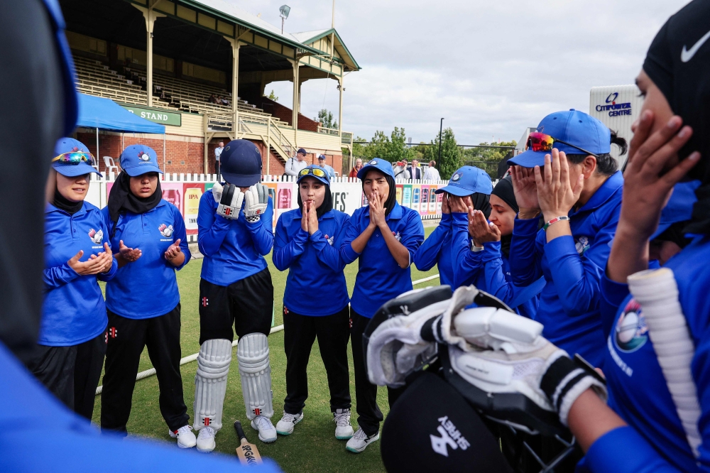 Afghanistan Women's XI players say a prayer before the cricket match between Afghanistan Women's XI and Cricket Without Borders XI at Junction Oval in Melbourne on January 30, 2025. (Photo by Martin Keep / AFP)