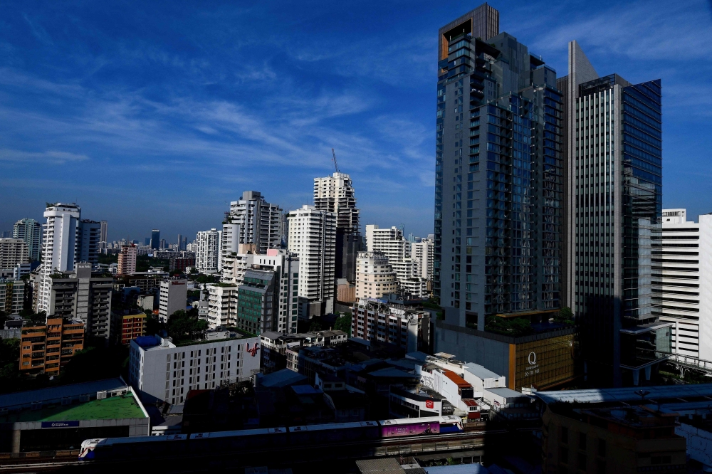 A general view shows a BTS commuter train as it passes with the backdrop of the Bangkok skyline on June 2, 2023. Photo by Manan VATSYAYANA / AFP