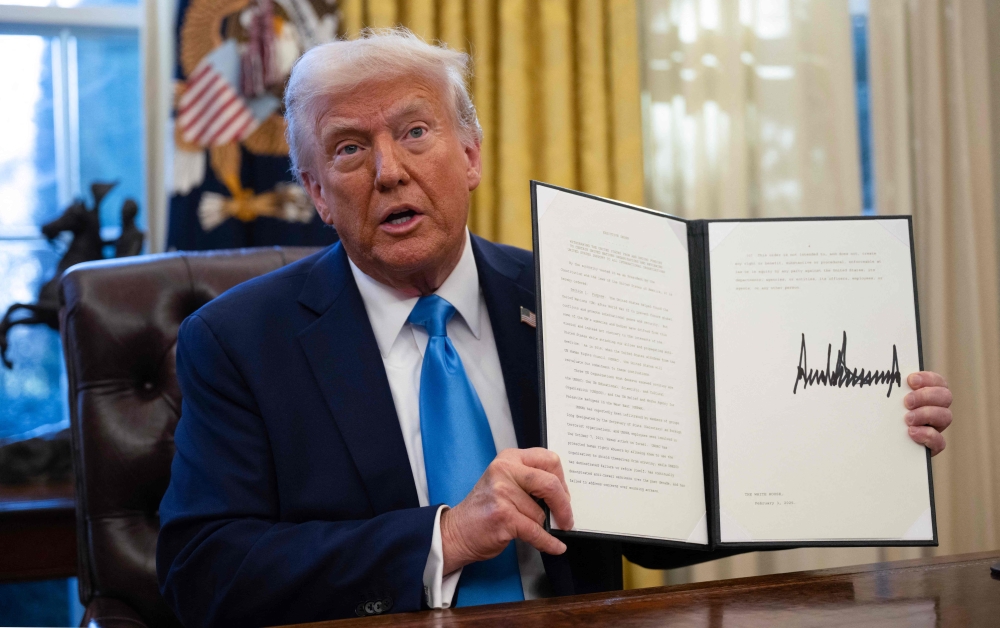 US President Donald Trump shows an executive order withdrawing his country from a number of United Nations bodies in the Oval Office of the White House on February 4, 2025 in Washington, DC. (Photo by Andrew Caballero-Reynolds / AFP)