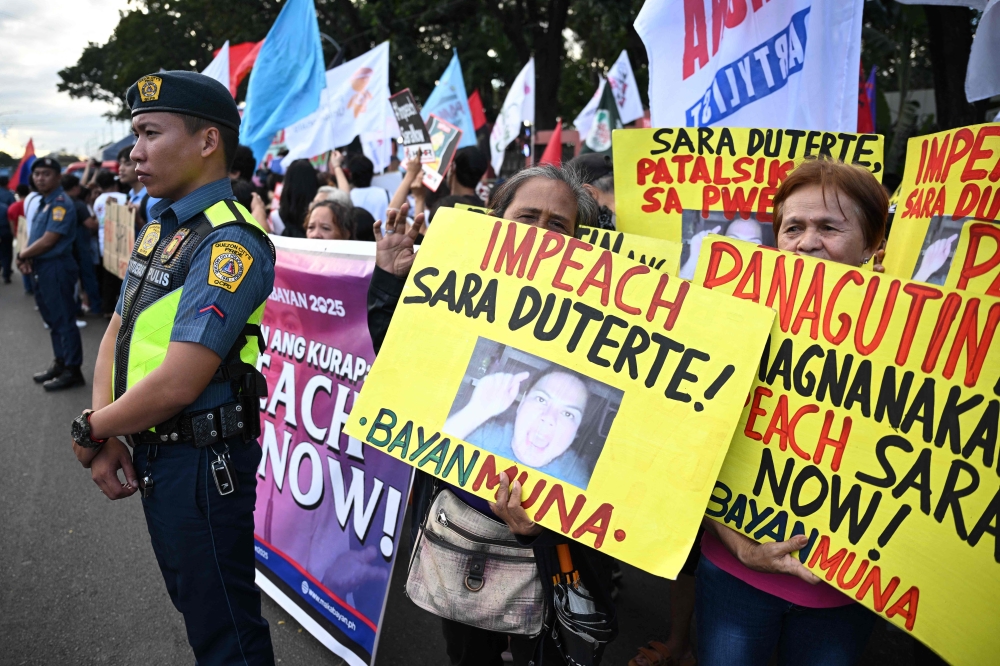 Protesters carry placards during a rally in front of the House of Representatives in Manila on February 5, 2025, as lawmakers voted to impeach Philippine Vice-President Sara Duterte. (Photo by Ted Aljibe / AFP)