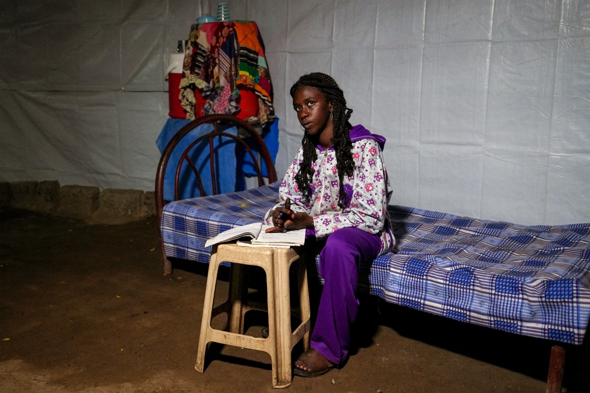 Teenage Sudanese rapper Hanim Mohamed (14), also known as Nana, poses for a picture while writing in a notebook inside a tent at the Zaeem al-Azhary School Shelter in Port Sudan on January 15, 2025. (Photo by AFP)
