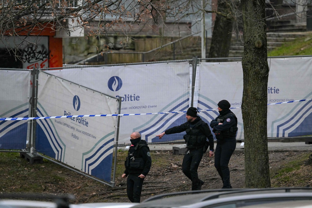 Police officers walk near a police fence blocking off an investigation area at the 