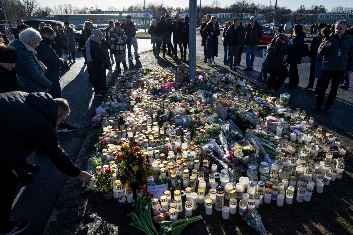 Mourners leave flowers and candles at the memorial site outside the adult education center Campus Risbergska school in Orebro, Sweden, on February 6, 2025 two days after a shooting there left eleven people dead. Photo by Christine Olsson/TT / TT NEWS AGENCY / AFP