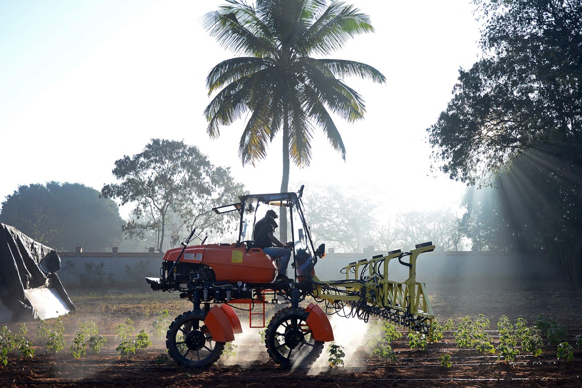 This photograph taken on February 3, 2025 shows workers at agritech startup Niqo Robotics, riding a tractor with AI-powered spot sprayer at a testing facility on the outskirts of Bengaluru. Photo by AFP