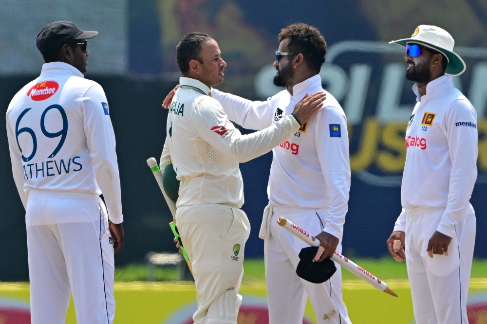 Australia's Usman Khawaja (2L) congratulates Sri Lanka's Dimuth Karunaratne (2R), who played his career's last match as Sri Lanka's Angelo Mathews (L) and Dinesh Chandimal (R) watch in Galle on February 9, 2025.  (Photo by Ishara S. Kodikara / AFP)