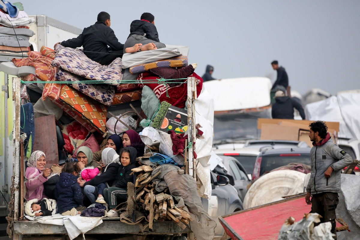 Displaced Palestinians sit in the back on a loaded truck on Salah al-Din road in al-Mughraqa in the central Gaza Strip, on February 10, 2025. (Photo by Eyad BABA / AFP)
