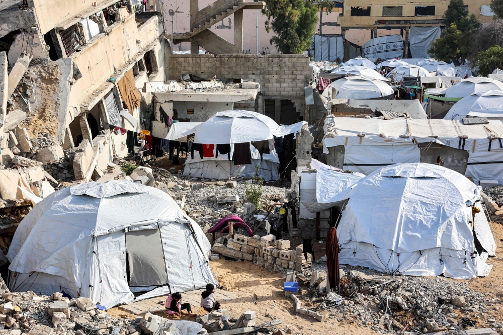 This view shows the tents of displaced Palestinians erected by a collapsed building in Gaza City on December 11, 2024. (Photo by Omar Al-Qattaa / AFP)