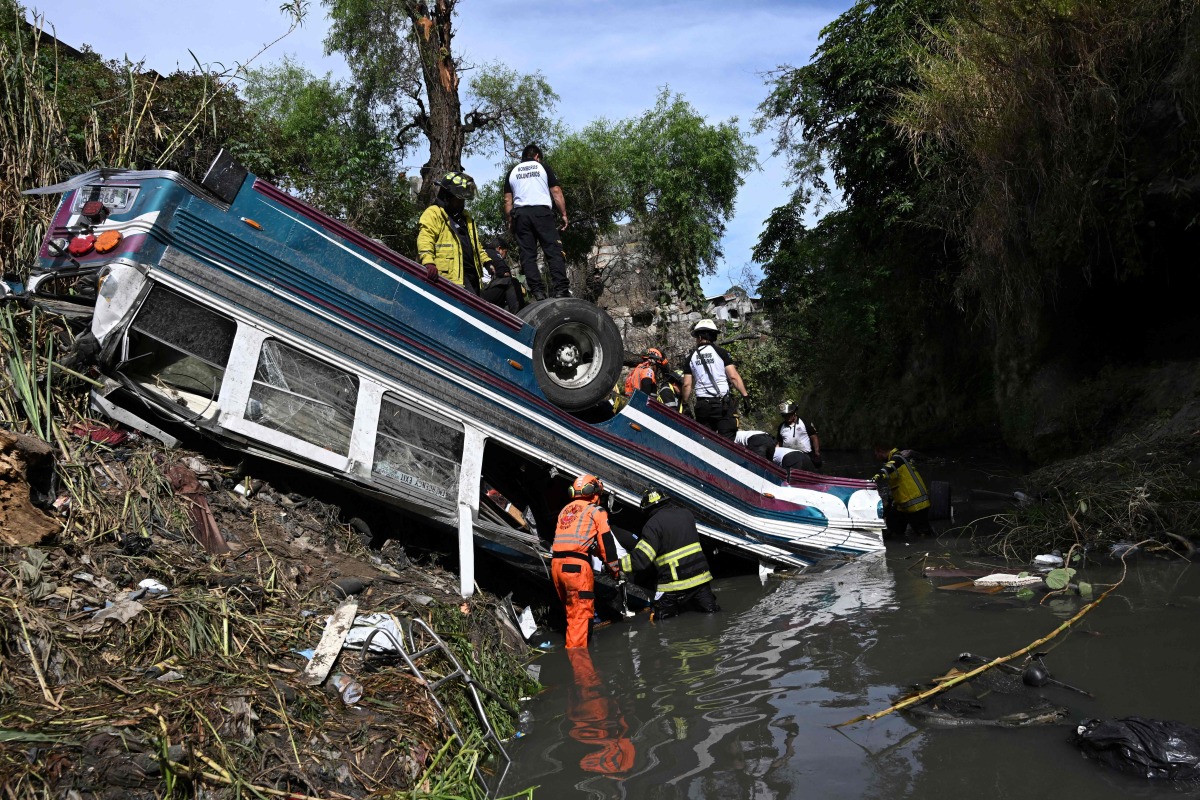 Firefighters work at the scene of an accident in which a bus fell down a ravine in Guatemala City on February 10, 2025. Photo by Johan ORDONEZ / AFP