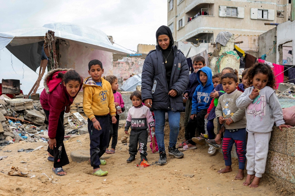 Children play with marbles near destroyed buildings at the Shati camp for Palestinian refugees north of Gaza City on February 11, 2025 amid the current ceasefire deal in the war between Israel and Hamas. (Photo by Bashar Taleb / AFP)