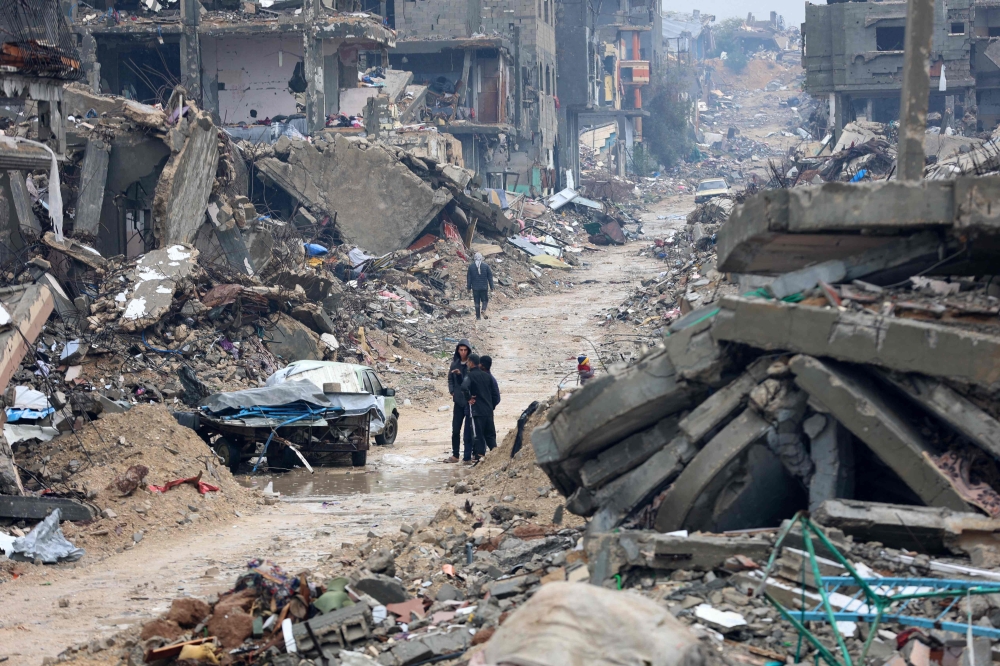 Palestinians walk amid the devastation in Beit Hanun in the northern Gaza Strip on February 12, 2025. (Photo by Omar Al-Qattaa / AFP)