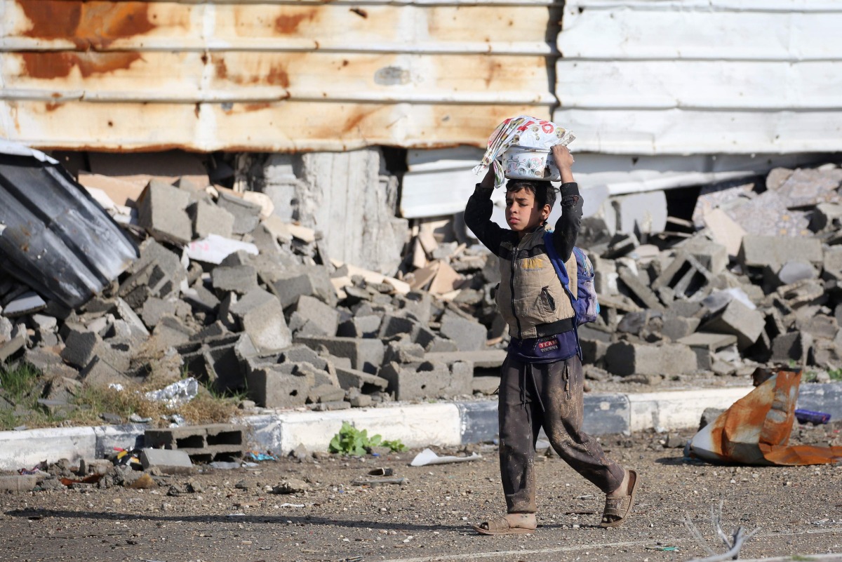 A Palestinian boy carries a container on his head in al-Mughraqa in the central Gaza Strip, on February 13, 2025. Photo by Eyad BABA / AFP