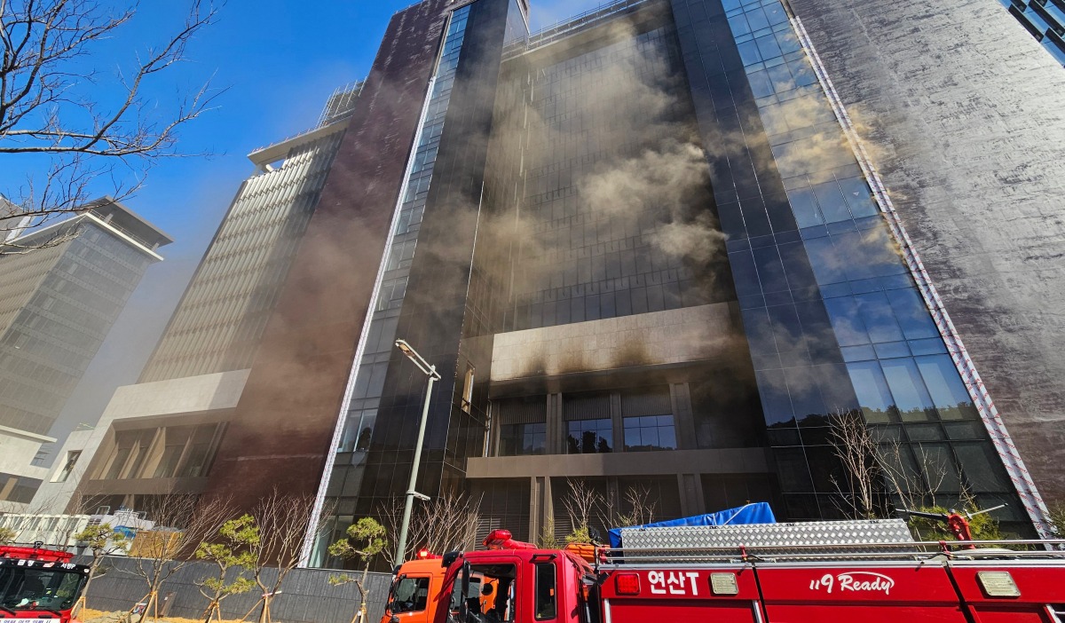 Firefighters work at the scene of a fire at a construction site of the Banyan Tree Hotel in the southern port city of Busan on February 14, 2025. (Photo by YONHAP / AFP) 