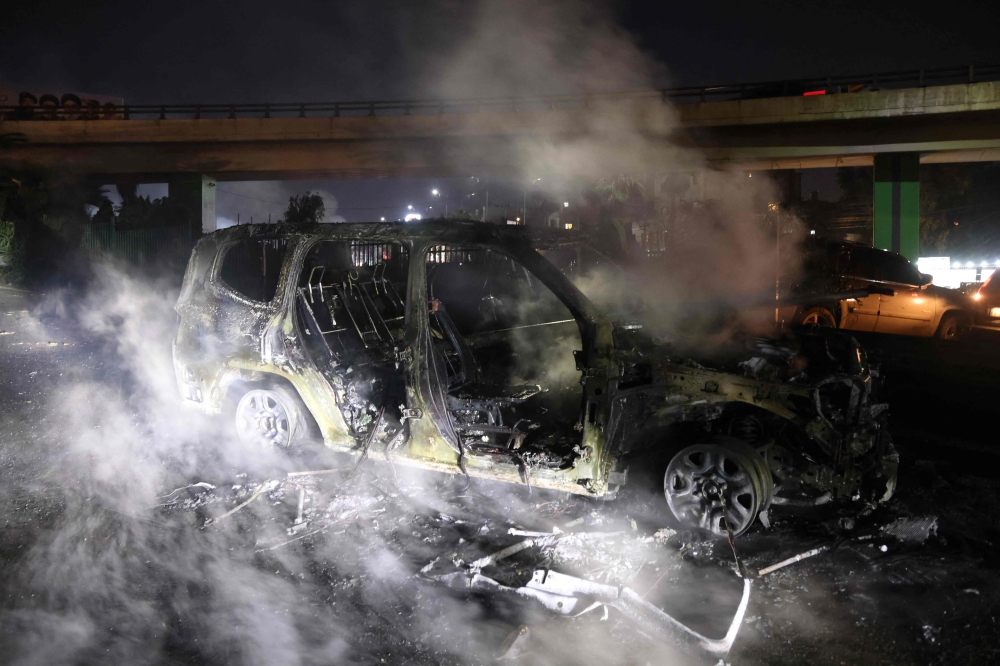 Smoke billows from the burnt remains of a UNIFIL vehicle, set ablaze by protesters, on the road leading to Beirut's international airport on February 14, 2025. (Photo by Ibrahim Amro / AFP)