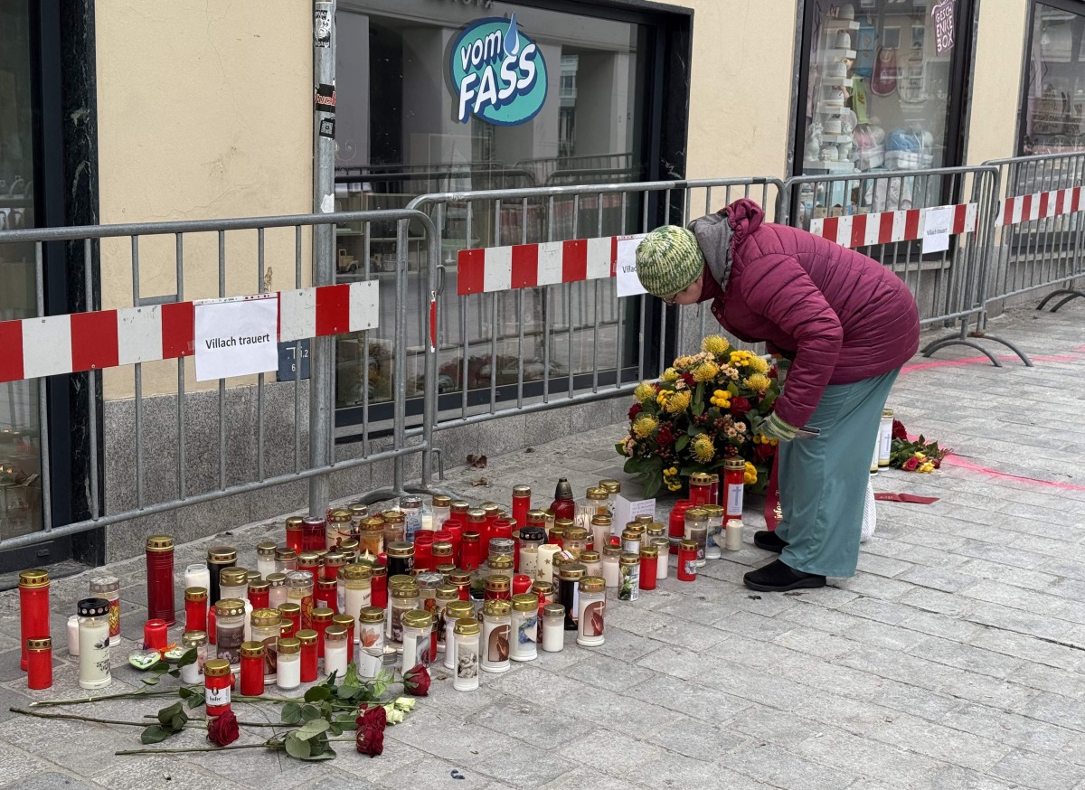 A woman stands at a makeshift memorial of candles and flowers placed on February 16, 2025 at the site where a man randomly attacked passers-by with a knife and stabbed to death a teenager and wounded five other people in Villach, Austria. Photo by GERD EGGENBERGER / APA / AFP