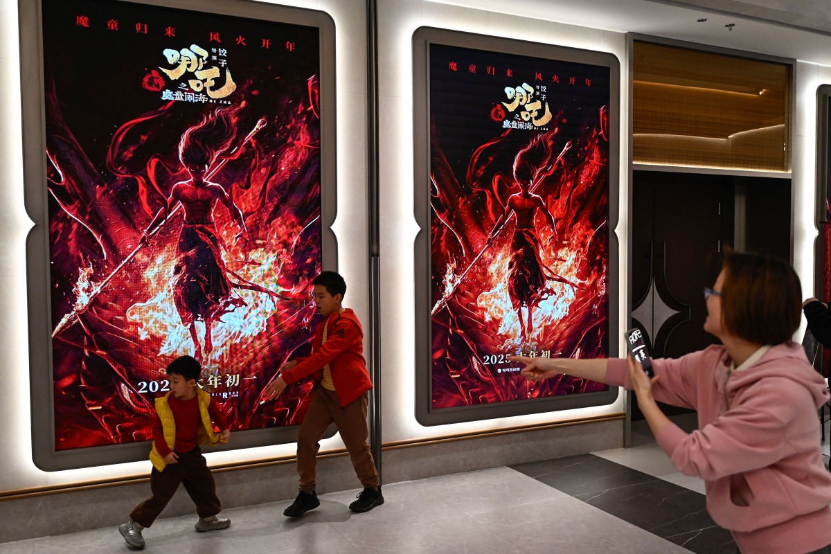 Children pose for a picture as they visit a movie theatre to watch the animated film Nezha 2 in Beijing on February 16, 2025. (Photo by Pedro PARDO / AFP)