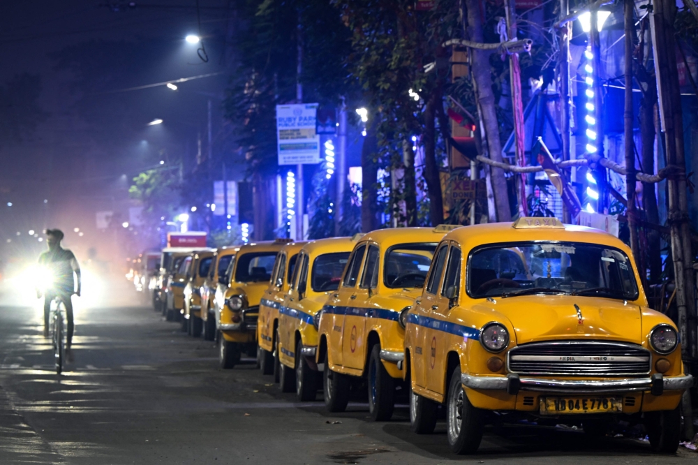 This photograph taken on February 1, 2025 shows Hindustan Ambassador yellow taxis parked along a roadside in Kolkata. (Photo by Dibyangshu Sarkar / AFP) 