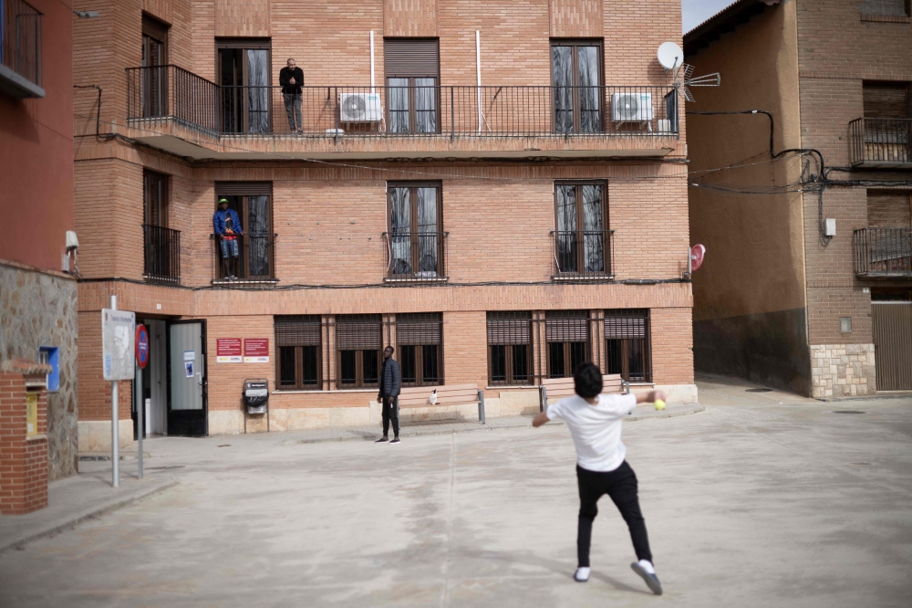 Refugees play with a ball in front of Accem association's residence, in Burbaguena, near Teruel, on February 10, 2025. (Photo by Josep LAGO / AFP)
 