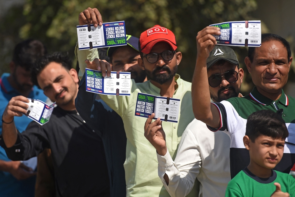 Spectators display their match tickets while waiting to enter the National Stadium in Karachi on February 19, 2025. (Photo by Rizwan Tabassum / AFP)