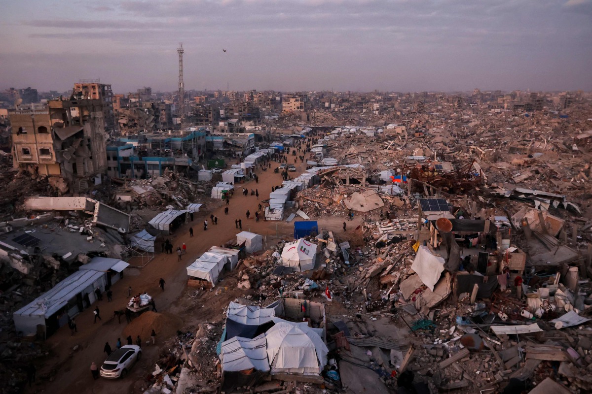 Palestinians walk past tents lining the streets amid the rubble of destroyed buildings in Jabalia, in the northern Gaza Strip on February 18, 2025. Photo by Omar AL-QATTAA / AFP