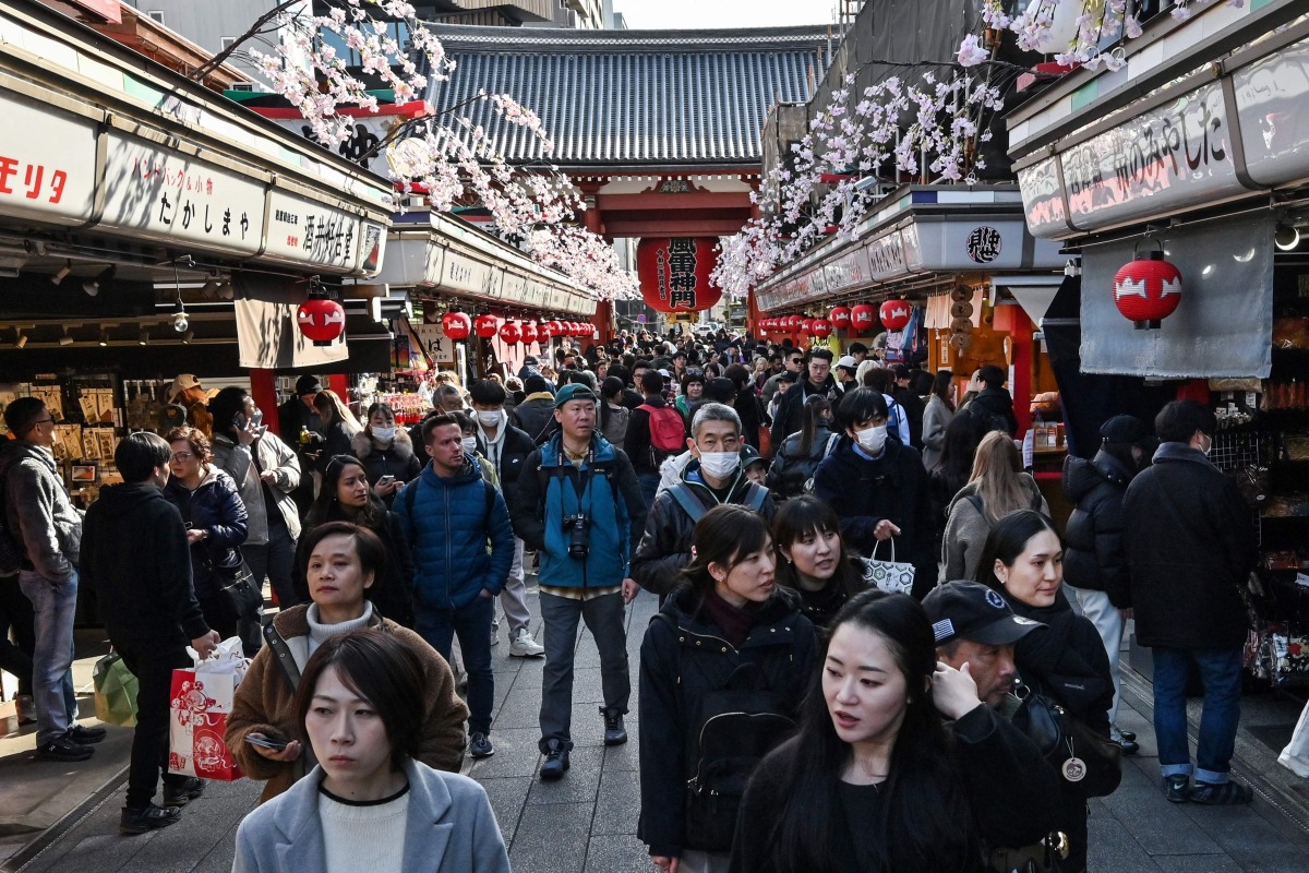 People walk along the main shopping street at Sensoji Temple in the popular tourist destination of Asakusa in central Tokyo on February 21, 2025. Photo by Richard A. Brooks / AFP