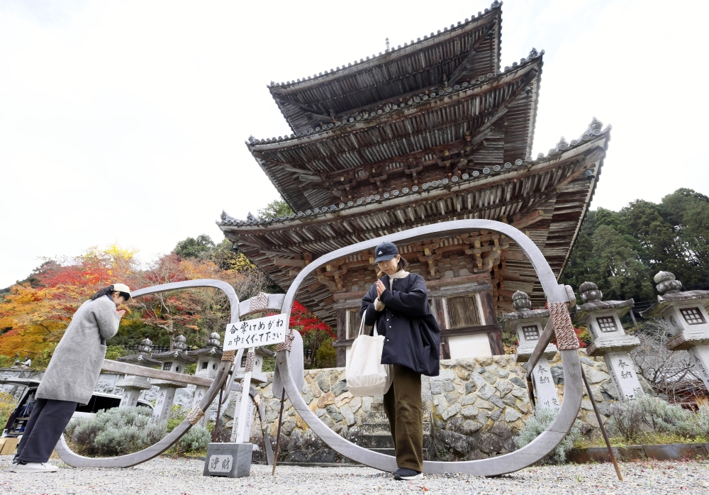 A large pair of glasses frames is seen in front of the three-story pagoda at Tsubosakadera temple in Takatori, Nara Prefecture. MUST CREDIT: The Japan News