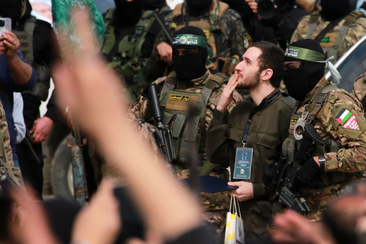 Israeli hostage Omer Shem Tov and Palestinian Hamas fighters after being released along with two others as part of the seventh hostage-prisoner exchange ,in Nuseirat in the central Gaza Strip, on February 22, 2025. (Photo by Bashar TALEB / AFP)
