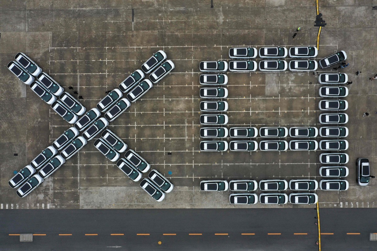 An aerial photo shows X9 electric vehicles by Chinese EV manufacturer XPeng, waiting to be loaded on a ship of the NYK line for Thailand during a ceremony in the Port of Guangzhou, China's southern Guangdong province on February 22, 2025. (Photo by Pedro Pardo / AFP)