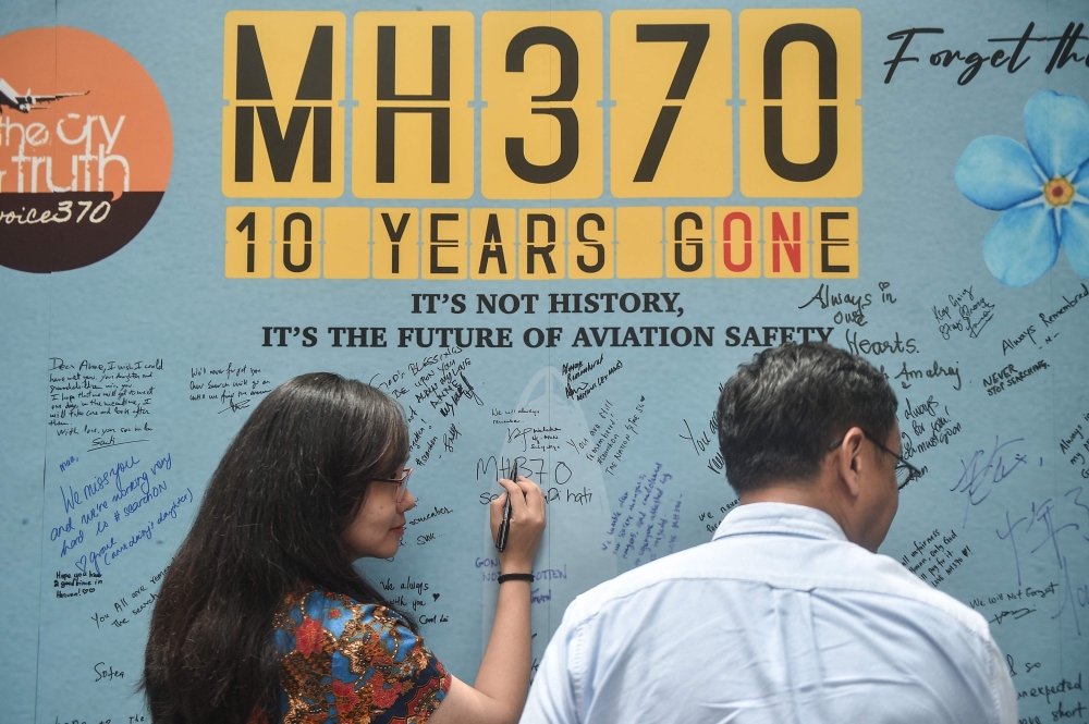 (Files) A woman writes a message during an event held by relatives of the passengers and supporters to mark the 10th year since the Malaysia Airlines flight MH370 disappeared from radar, in Subang Jaya on March 3, 2024. (Photo by Arif Kartono / AFP)