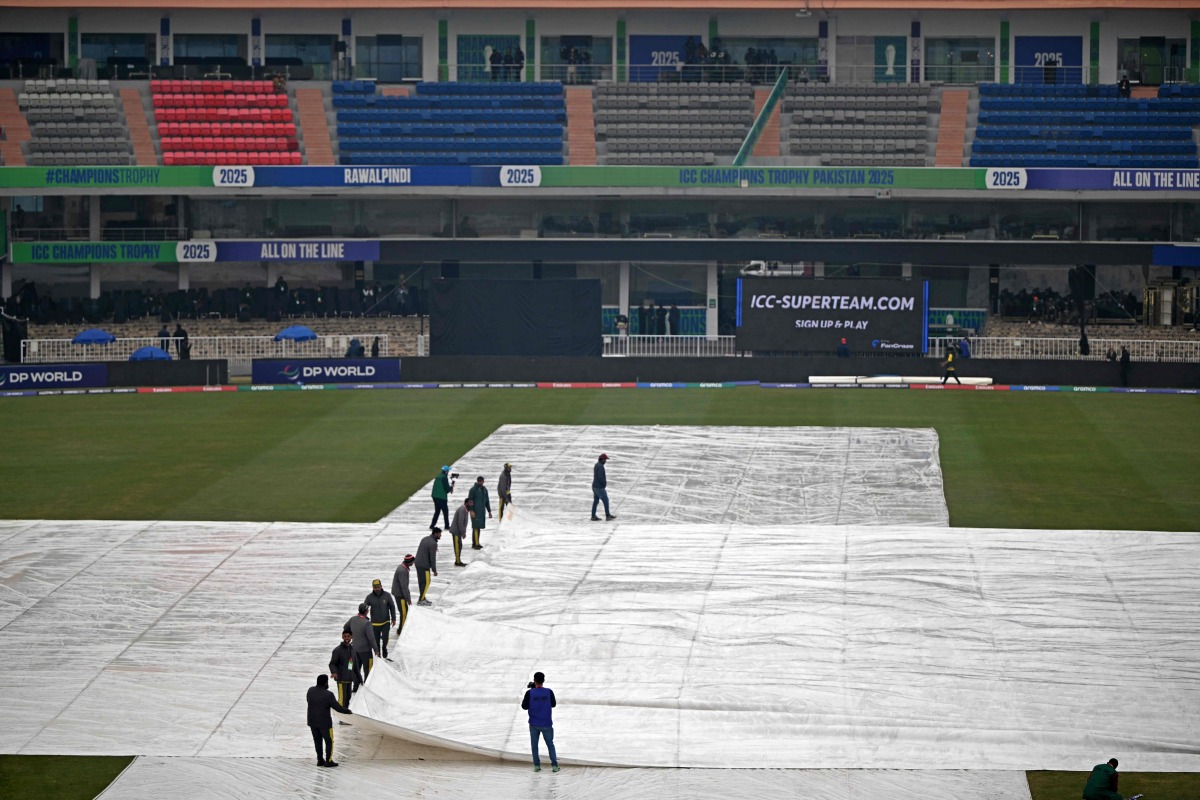 Groundmen cover the pitch as it rains before the start of the ICC Champions Trophy one-day international (ODI) cricket match between Australia and South Africa at the Rawalpindi Cricket Stadium in Rawalpindi on February 25, 2025. (Photo by Farooq NAEEM / AFP)
