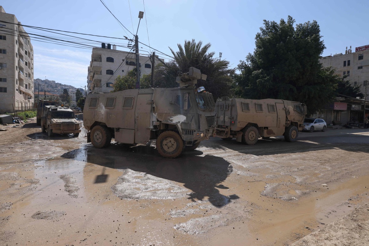 Vehicles of Israeli occupation forces drive down a road amid a weeks-long offensive at the Jenin refugee camp in the occupied West Bank on February 25, 2025. (Photo by Jaafar ASHTIYEH / AFP)
