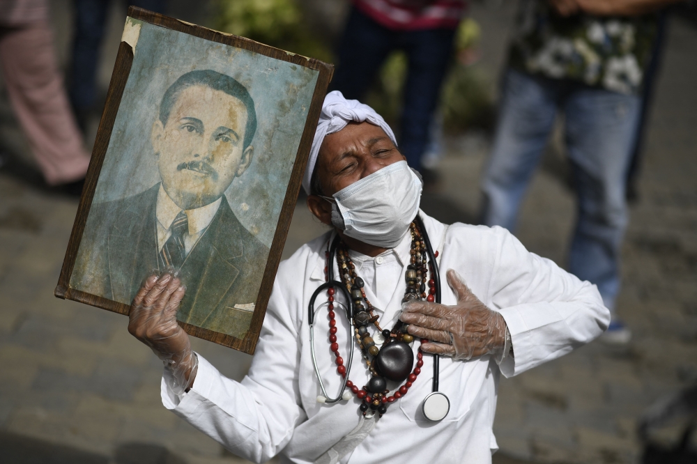 File: A woman holds a portrait of Venezuelan doctor Jose Gregorio Hernandez, also called 