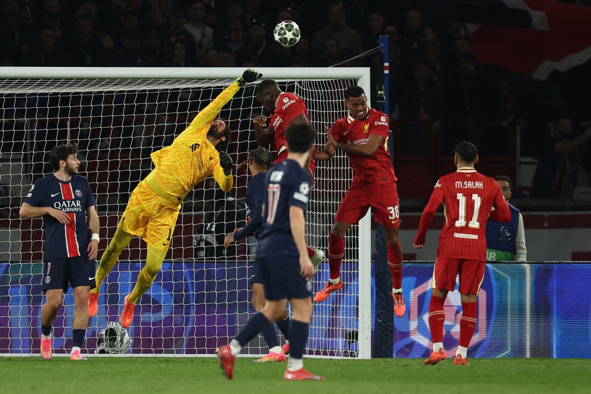 Liverpool's Brazilian goalkeeper #01 Alisson (2L) punches the ball as he makes a save during the UEFA Champions League Round of 16 first leg football match between Paris Saint-Germain (FRA) and Liverpool (ENG) at the Parc des Princes stadium in Paris on March 5, 2025. (Photo by Anne-Christine POUJOULAT / AFP)
