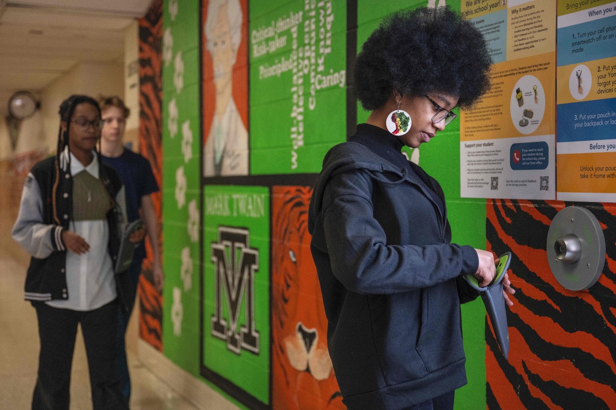 Eighth-grader Ja’ Nae Dorsey (R) unlocks her cell phone pouch after school followed by her twin sister La’ Mae Dorsey (L) and 7th-grader Hayden Jones (C) at Mark Twain Middle School in Alexandria, Virginia, on March 6, 2025. Photo by Jim WATSON / AFP