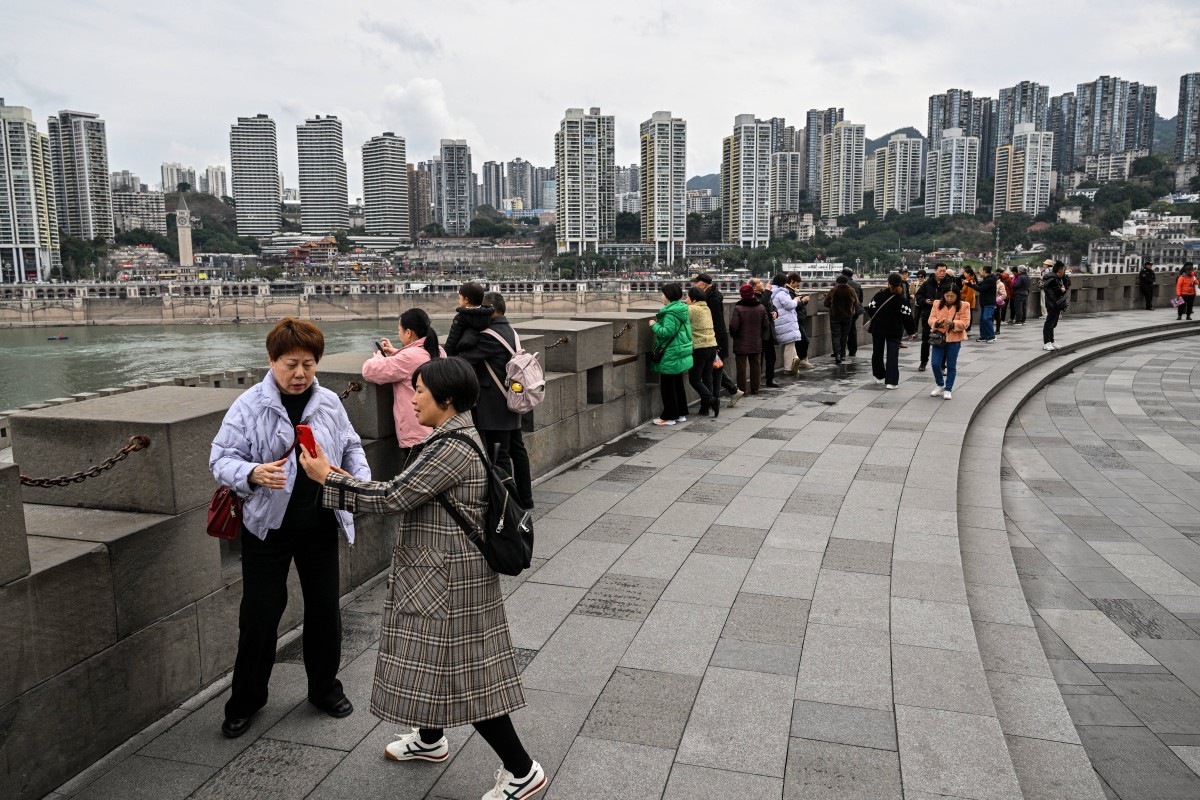 People look at the skyline next to the Jialing river in Yuzhong District in Chongqing in southwestern China on March 6, 2025. (Photo by Hector RETAMAL / AFP)