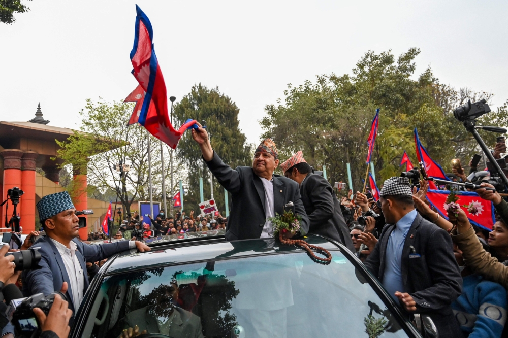 Nepal's former King Gyanendra Bir Bikram Shah Dev waves as he arrives at Tribhuwan International Airport in Kathmandu on March 9, 2025. (Photo by Prakash Mathema / AFP)