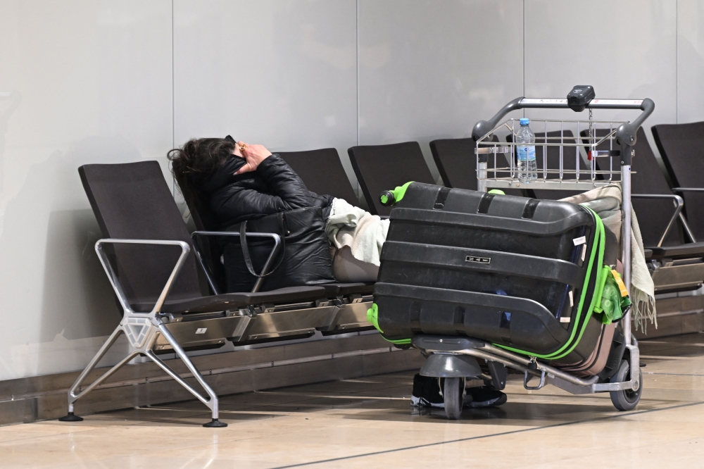 A passenger sleeps at the empty Berlin-Brandenburg Airport's Terminal during a strike of German union Verdi at the Berlin-Brandenburg Airport (BER) in Schoenefeld, southeast of Berlin, on March 10, 2025. (Photo by Ralf Hirschberger / AFP)