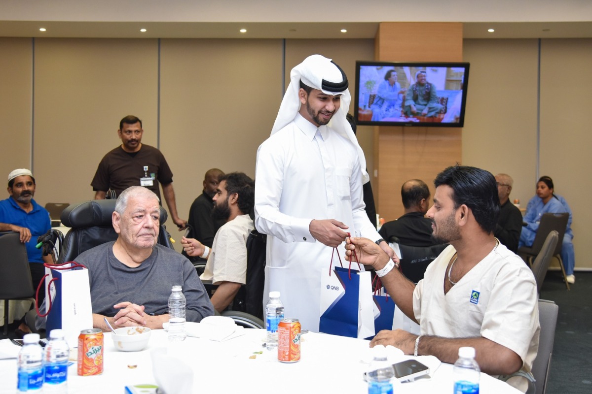 A QNB official distributing gift to a patient during the Ramadan Iftar.