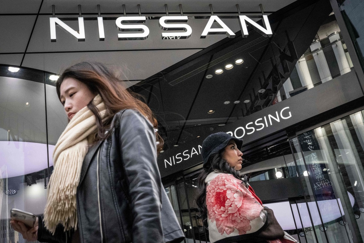 This picture taken on February 5, 2025 shows pedestrians walking past a showroom for Japanese automaker Nissan in Tokyo. Photo by Yuichi YAMAZAKI / AFP