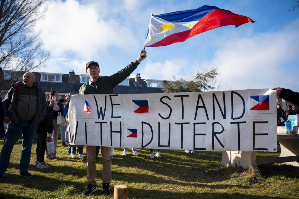 A demonstrator waves a Philippines national flag and holds a banner reading 