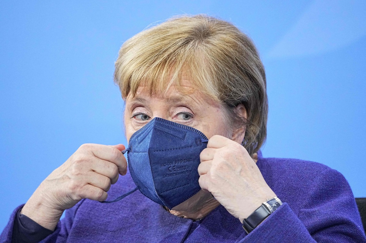 Then German Chancellor Angela Merkel puts onher face mask as she leaves after addressing a press conference following a video meeting with the heads of government of Germany's federal states at the Chancellery in Berlin on November 18, 2021, amid the novel coronavirus / COVID-19 pandemic. Photo by Michael Kappeler / POOL / AFP