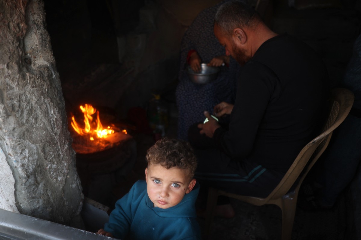 A child looks on as his family prepares a fast-breaking iftar meal in the Bureij camp for Palestinian refugees in the central Gaza Strip on March 11, 2025 during the Muslim holy fasting month of Ramadan. (Photo by Eyad BABA / AFP)