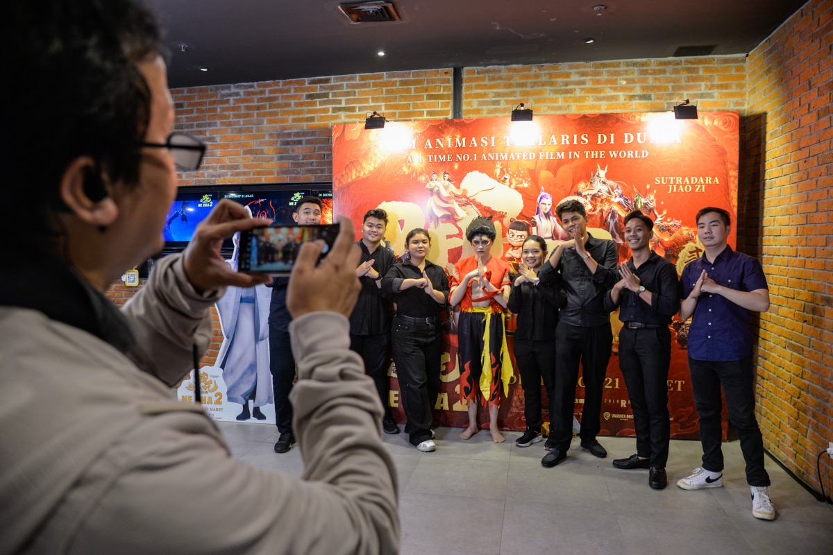 People pose for photos in front of a poster of Chinese animated film Ne Zha 2 at CGV Grand Indonesia in Jakarta, Indonesia, March 15, 2025. (Xinhua/Xu Qin)
