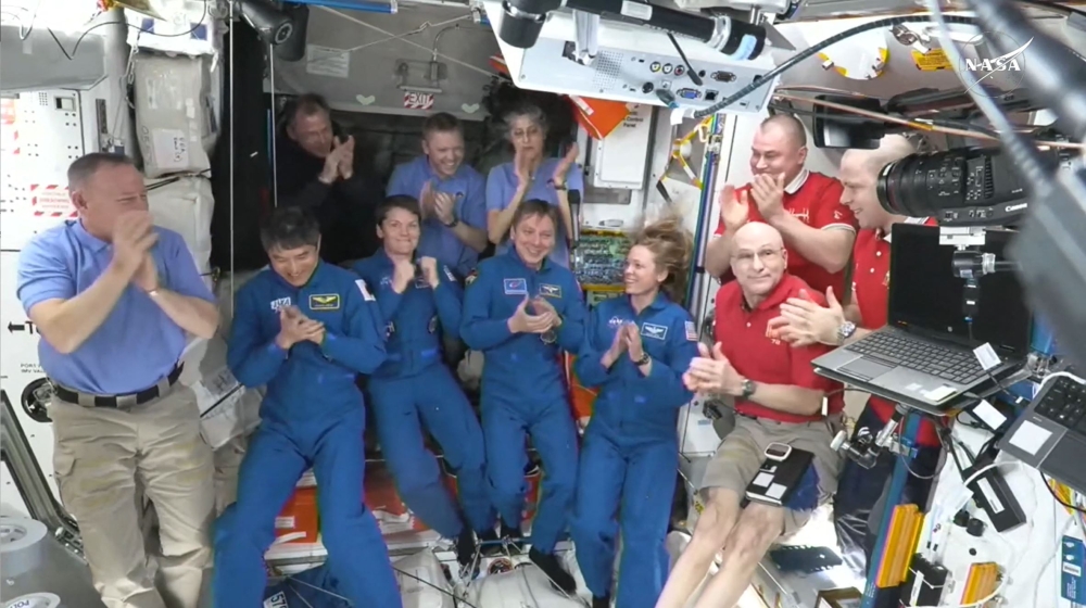 This screengrab made from a NASA livestream shows the SpaceX Dragon Crew-10 members (C, in dark blue) NASA astronauts Anne McClain and Nichole Ayers, JAXA (Japan Aerospace Exploration Agency) astronaut Takuya Onishi, and Roscosmos cosmonaut Kirill Peskov, clapping after entering the International Space Station flanked by NASA astronauts Butch Wilmore, Suni Williams, Nick Hague and Don Pettit and Russian cosmonauts Aleksandr Gorbunov, Alexey Ochinin and Ivan Vagner, on March 16, 2025. (Photo by NASA / AFP)