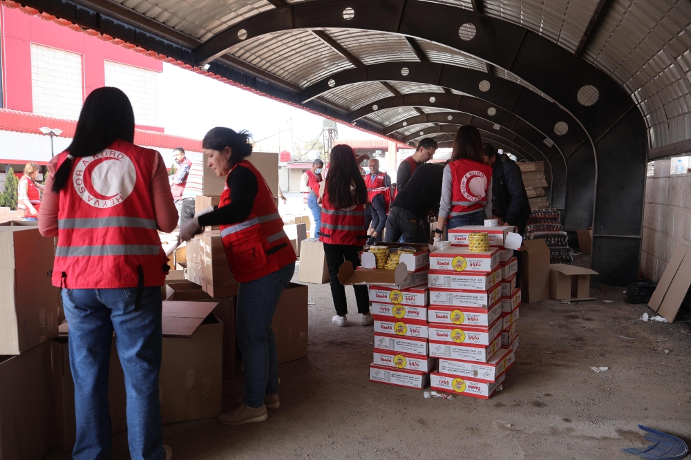 A handout picture provided by Syria's Kurdish Red Crescent shows members of the emergency charity group preparing humaintarian aid boxes, in the northeastern city of Qamishli on March 16, 2025. (Photo by Kurdish Red Crescent / AFP) 