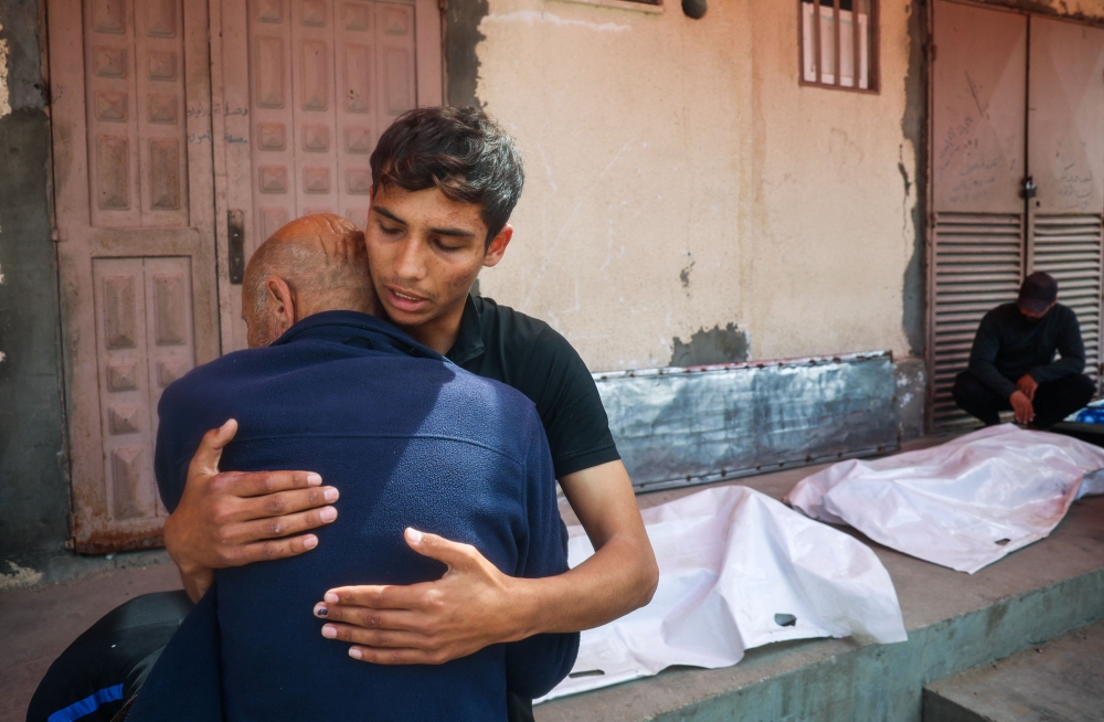 Relatives mourn by the bodies of three Palestinian men killed in an Israeli drone strike east of the Bureij camp, at the al-Aqsa Martyrs hospital in Deir el-Balah in the central Gaza Strip on March 17, 2025. (Photo by Eyad Baba / AFP)