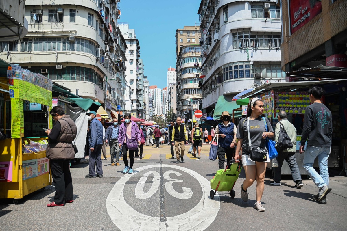 Pedestrians walk along a street in Hong Kong on March 19, 2025. (Photo by Peter PARKS / AFP)